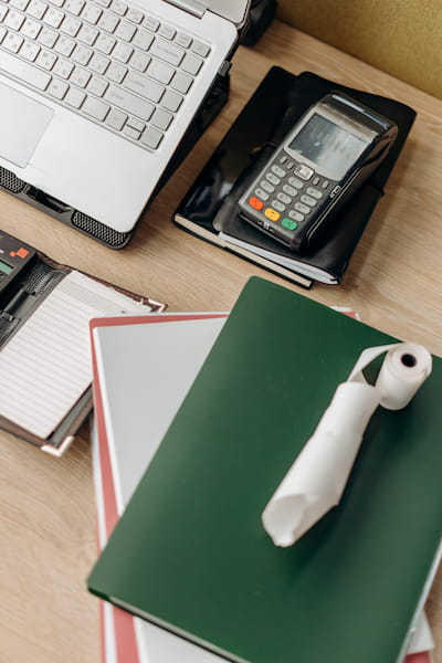 Mesa com alguns cadernos, calculadora e computador.